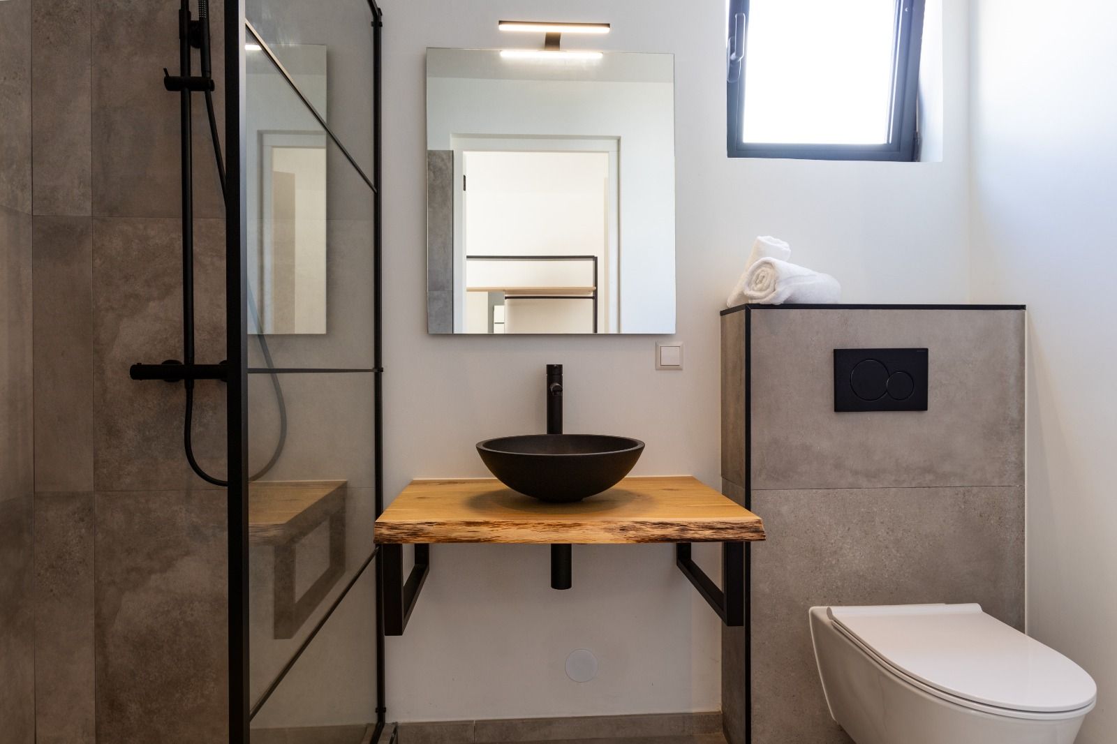 Badkamer met houten wastafelmeubel en zwarte kom